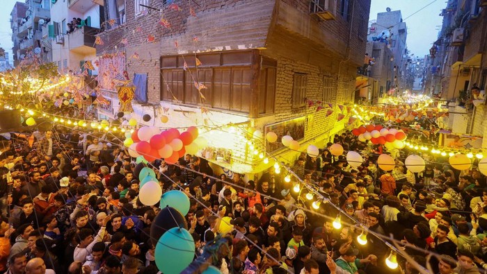 Keseruan Berbuka Puasa Bersama di distrik Mataria Kairo Mesir Egyptian residents of Ezbet Hamada in Cairo's Mataria district look out their windows and balconies to celebrate a mass ''Iftar'', the meal to end their fast at sunset, during the holy fasting month of Ramadan in Cairo, Egypt March 25, 2024. REUTERS/Amr Abdallah Dalsh