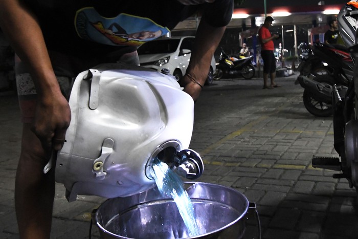 Seorang teknisi menumpahkan isi tangki bensin motor yang mogok  ke dalam dirigen usai mengisi di salah satu pom bensin di Jalan Ir Juanda, Bekasi, Jawa Barat, Selasa (26/3/2024) dini hari Menurut keterangan konsumen yang terdampak sebanyak puluhan kendaraan bermotor mogok usai isi bensin dan pihak dari pom bensin mengganti 100 persen biaya kerusakan kendaraan yang rusak. ANTARA FOTO/ Fakhri Hermansyah/foc.