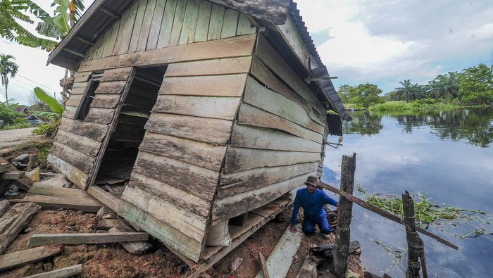 Warga mengambil sisa-sisa kayu di samping rumahnya yang hampir roboh akibat terseret tumpukan gulma atau rumput kumpeh di Tanjung, Kumpeh, Muaro Jambi, Jambi, Senin (25/3/2024). Belasan rumah di bantaran Sungai Kumpeh tersebut roboh akibat terseret tumpukan gulma yang hanyut terbawa arus sungai itu. ANTARA FOTO/Wahdi Septiawan/YU