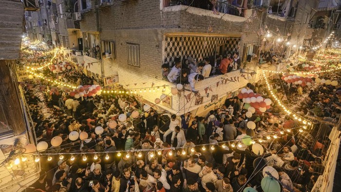 Residents of Ezbet Hamada in Cairo's El Matareya district peer from their balconies to celebrate a mass breakfast, 