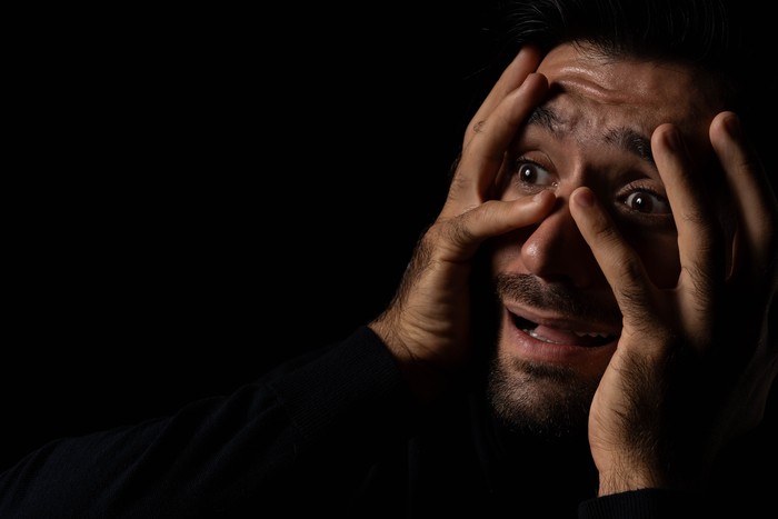 Pria ketakutan Frightened young beard man afraid scared and terrified with fear expression face He put hands on face Young guy were shock and panic in the horror dark room Emotional and facial expression concept