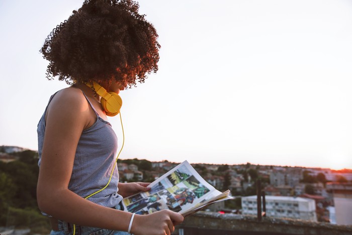 Portrait of a teenage girl on a rooftop. Reading a comic. Enjoying the sunset.