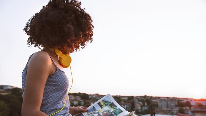 Portrait of a teenage girl on a rooftop. Reading a comic. Enjoying the sunset.