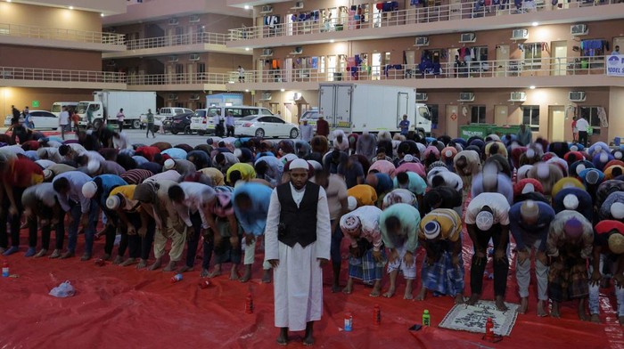 Muslims pray at charity Iftar camp, with workers housings visible in the background, during the Muslim holy month of Ramadan in Dubai, United Arab Emirates, March 26, 2024. REUTERS/Amr Alfiky