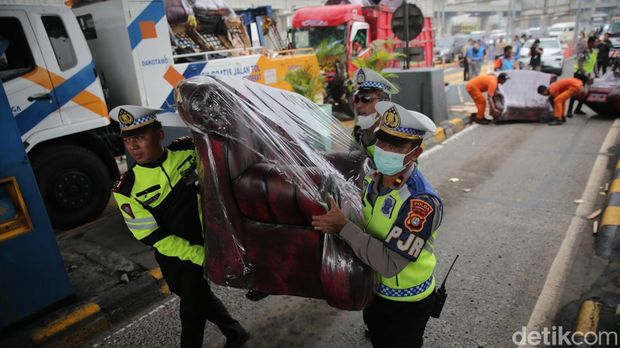Petugas mengevakuasi kendaraan yang terlibat kecelakaan di Gerbang Tol Halim Utama, Jakarta Timur, Rabu (27/3/2024).