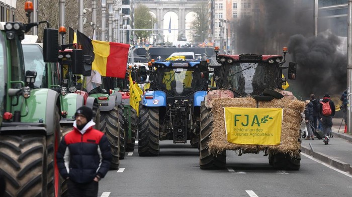 Demo Petani Belgia Berujung Ricuh di Markas Uni Eropa Smoke rises next to tractors as Belgian farmers take part in a protest over price pressures, taxes and green regulation, on the day of an EU agriculture ministers' meeting in Brussels, Belgium March 26, 2024. REUTERS/Yves Herman