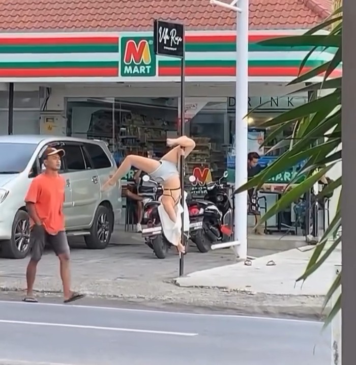 Aksi nyeleneh bule perempuan yang meliuk-liuk di tiang papan nama sebuah toko di Canggu, Bali, Kamis (28/3/2024). (Tangkapan layar)