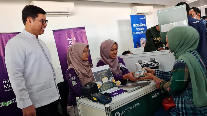 Direktur Utama PT Bank Muamalat Indonesia Tbk Indra Falatehan (kiri) dan Sekretaris Perusahaan Bank Muamalat Hayunaji (kanan) berfoto bersama masyarakat yang menukarkan uang rupiah di gerai Bank Muamalat di Istora Senayan, Jakarta, Kamis (28/3). Bank Muamalat menyiapkan uang tunai senilai Rp 736 miliar untuk melayani kebutuhan transaksi selama Ramadan dan Idul Fitri 2024.
