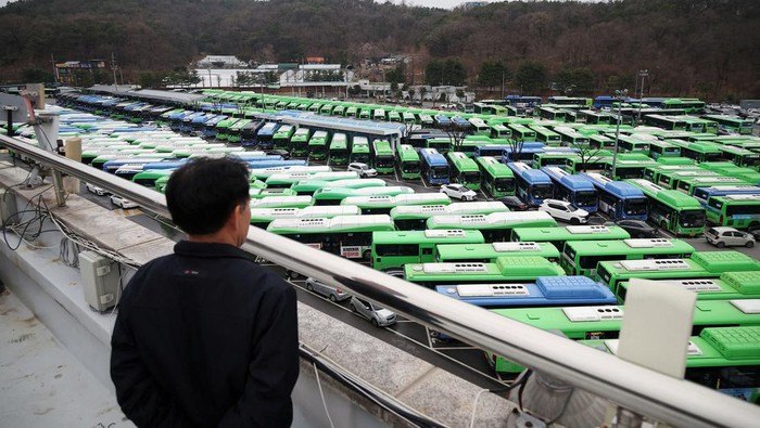 A bus driver walks past buses parked at a depot, as bus drivers go on strike, in Seoul, South Korea, March 28, 2024.   REUTERS/Kim Hong-Ji