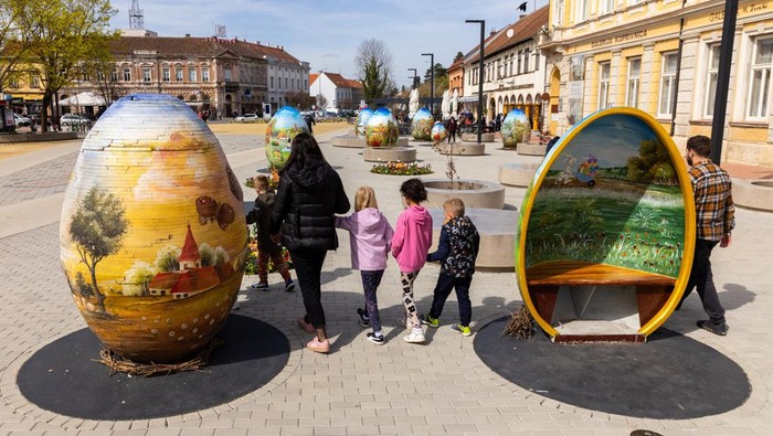 A man walks next to structures depicting Easter eggs painted in the traditional naive art style in Koprivnica, Croatia, March 27, 2024. REUTERS/Antonio Bronic