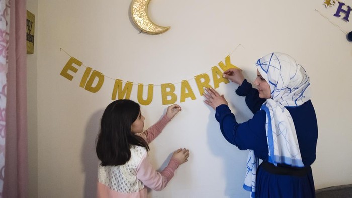 North-American muslim mother and daughter decorating home for Ramadan. Girl is wearing a traditional moroccan dress, mother is wearing a hijab. Horizontal waist up indoors shot with copy space. This was taken in Quebec, Canada.