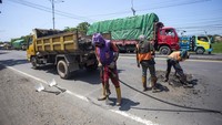Pekerja melakukan penambalan jalan di jalur pantura Susukan, Cirebon, Jawa Barat, Jumat (29/3/2024).