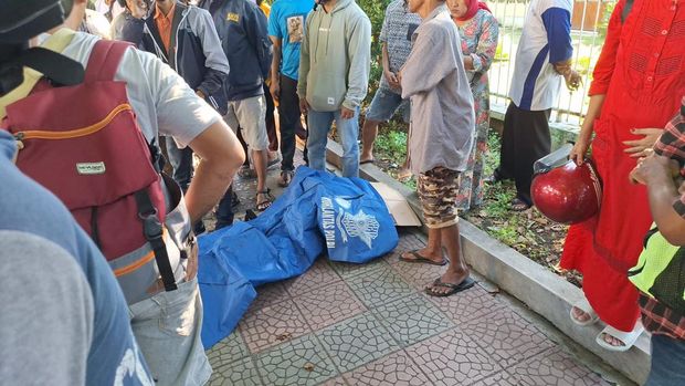 Petugas kepolisian mengevakuasi jasad Yoyok Sumaryono yang ditemukan di trotoar.