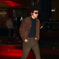 Masuk malam hari, ia tampil dengan kemeja polos gelap yang dipasangkan dengan celana coklat berpotongan langsing. Jaket dan sepatu senada juga jadi andalan. (Foto: Jose Perez/Bauer-Griffin/GC Images)