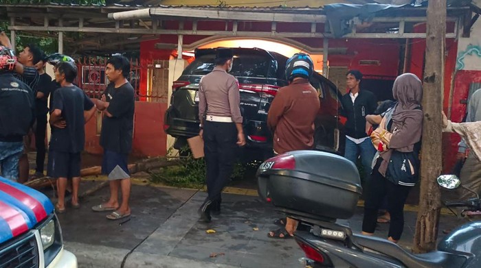 Polisi melakukan olah TKP mobol Fortuner menabrak rumah warga.