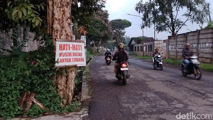 Tulisan peringatan akan bahaya lubang jalanan di depan, terpasang pada sebuah pohon di Jalan Alternatif Bandung-Sumedang via Simpang, Sabtu (30/3/2024).