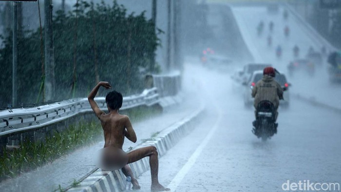 Seorang pria diduga Orang Dengan Gangguan Jiwa (ODGJ) terlihat di Jalan Pengairan 2, Margajaya, Bekasi. Pria mandi hujan dengan telanjang bulat.
