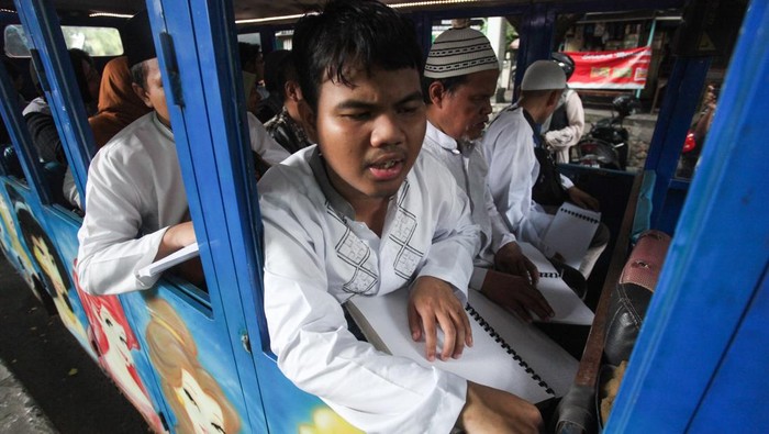 Sejumlah penyandang tuna netra membaca Al Quran braille di atas kereta kelinci di kawasan Taman Bungkul, Surabaya, Jawa Timur, Minggu (31/3/2024). Khataman Al Quran braille di atas kereta kelinci dengan berkeliling tersebut bertujuan mengajak umat Islam untuk membaca Al Quran. ANTARA FOTO/Didik Suhartono/YU