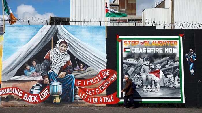 A man walks past pro-Palestinian murals on the International Wall in support of Gaza, amid the ongoing conflict between Israel and the Palestinian Islamist group Hamas, in Belfast, Northern Ireland, March 29, 2024. REUTERS/Clodagh Kilcoyne