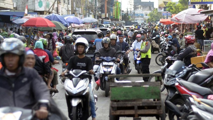 Petugas polisi mengatur lalu lintas kendaraan yang terhambat akibat pasar tumpah Pasir Gintung di Jalan Imam Bonjol, Tanjung Karang Pusat, Bandar Lampung, Lampung, Senin (1/4/2024). Para pedagang pasar tumpah tersebut menutup setengah badan jalan dan menyebabkan arus lalu lintas tersendat dan mengakibatkan kemacetan pada jam sibuk. ANTARA FOTO/Ardiansyah/foc.