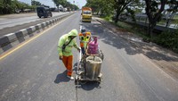 Pekerja menyelesaikan proses pengecatan marka jalan di jalur Pantura Lohbener Indramayu, Jawa Barat, Senin (1/4/2024).