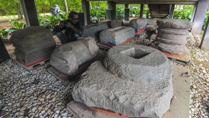 Pengunjung melihat koleksi temuan benda purbakala yang diterlantarkan di bawah bangunan berkonstruksi panggung di Kawasan Candi Kedaton, Kawasan Cagar Budaya Nasional (KCBN) Muara Jambi, Muaro Jambi, Jambi, Senin (1/4/2024). Belasan benda purbakala di antaranya beberapa arca, makara, dan padmasana peninggalan peradaban Candi Muara Jambi yang sebelumnya disimpan di ruang museum setempat kini terlantar di bawah bangunan panggung tanpa penutup selama hampir dua tahun. ANTARA FOTO/Wahdi Septiawan/nym.