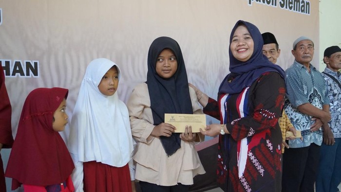 Bupati Sleman, Kustini Sri Purnomo menyerahkan bantuan bagi warga kurang mampu dan anak yatim, Selasa (2/4/2024).