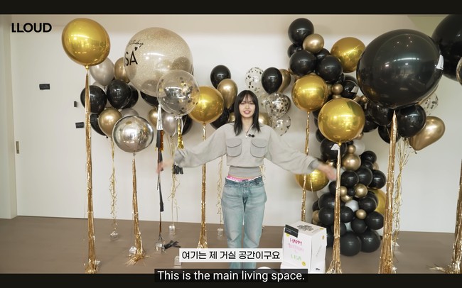 Berhubung konten tersebut diambil di hari ulang tahun Lisa BLACKPINK, ruangan utama rumahnya dipenuhi dengan dekorasi balon berwarna gold dan hitam. Lisa BLACKPINK mengatakan area tersebut biasanya dibiarkan kosong tanpa furnitur. Foto: dok. YouTube @wearelloud