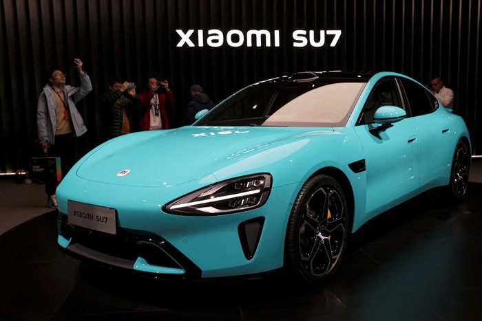 FILE PHOTO: Visitors film around Xiaomis first electric vehicle, the SU7, displayed at an event in Beijing, China December 28, 2023. REUTERS/Florence Lo/File Photo