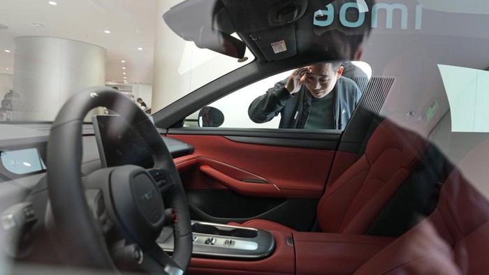 A man peeks at the interior of the Xiaomi SU7 electric car on display in Beijing, Tuesday, March 26, 2024. Xiaomi, a well-known smart consumer electronics brand in China, is joining the country's booming but crowded market for electric cars. (AP Photo/Ng Han Guan)