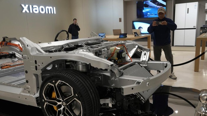 Visitors to the Xiaomi Automobile flagship store look at the insides of the Xiaomi SU7 electric car on display in Beijing, Tuesday, March 26, 2024. Xiaomi, a well-known smart consumer electronics brand in China, is joining the country's booming but crowded market for electric cars. (AP Photo/Ng Han Guan)