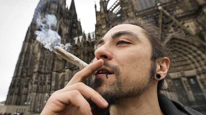 Resmi Dilegalkan, Warga Jerman Ramai-ramai Merokok Ganja A man smoking cannabis in front of the Cathedral in Cologne, Germany, on a public consumption event at the start of a new law on Monday, April 1, 2024. Germany has legalized the possession of small amounts of marijuana, the new law took effect Monday. (AP Photo/Martin Meissner)