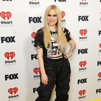 Avril Lavigne bergaya punk rock dengan cropped T-shirt, celana hitam dan boots. Foto: Getty Images/Frazer Harrison