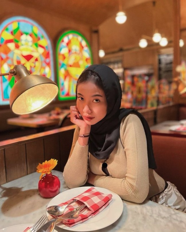 Ada momen di mana ia tampil kasual mengenakan cardigan cokelat dan celana motif yang atraktif saat makan di restoran. Kali ini gaya hijab Ghaniya Salma kembali memperlihatkan rambut bagian atas. Foto: Instagram @ghaniyasalma