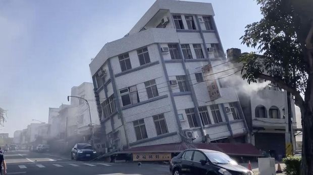 In this image taken from a video footage run by TVBS, a woman stands near a partially collapsed building in Hualien, eastern Taiwan on Wednesday, April 3, 2024. A powerful earthquake rocked the entire island of Taiwan early Wednesday, collapsing buildings in a city and creating a tsunami that washed ashore on Japanese islands. (TVBS via AP)