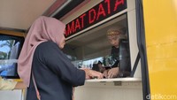 Seorang warga sedang menukar kupon dengan uang baru di mobil penukaran uang.