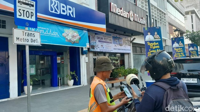 Aldi saat membayar parkir non tunai ke ukir e-parkir di Jalan Kesawan Medan menggunakan aplikasi BRImo (Andika Syahputra/detikcom)