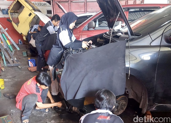 Fatiha Azza saat memperbaiki mobil pelanggan di bengkelnya