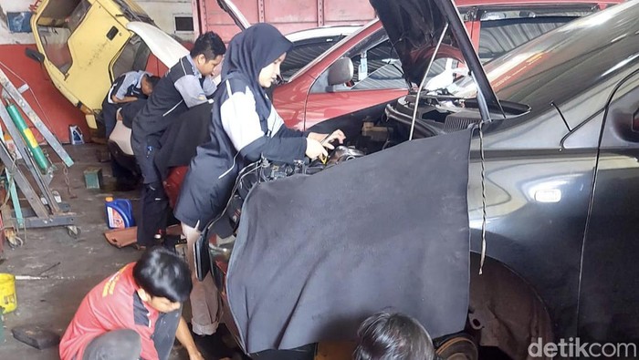 Fatiha Azza saat memperbaiki mobil pelanggan di bengkelnya