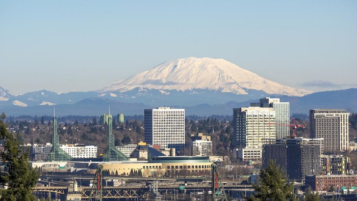 A view looking down to the Willamette River with trees, bridges, Convention Center, Skyscrapers and Mt St Helens (Washington State) in the background. This is  downtown Portland, Oregon area.