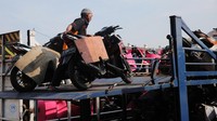 Petugas menaikkan motor-motor pemudik ke atas truk.