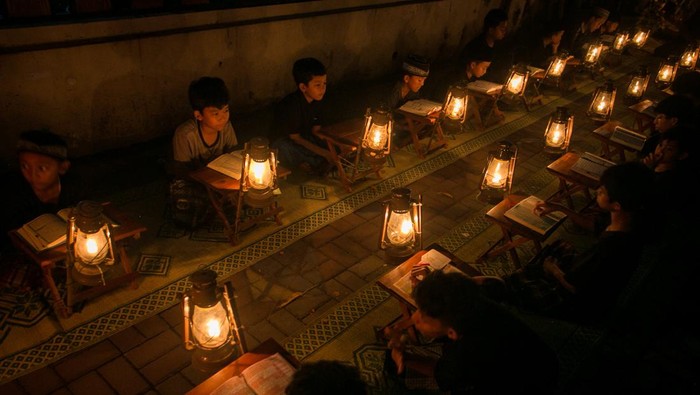 Seorang pembimbing mengajarkan seorang anak mengaji dengan penerangan lampu lilin saat pengajian Tadarus Al Quran di kampung Prajurit Wirotamtomo, Baluwarti, Solo, Jawa Tengah, Rabu (3/4/2024). Pengajian dalam rangka menyambut malam Lailatul Qadar tersebut untuk mendekatkan anak-anak dengan alam serta mendidik untuk rajin membaca Al Quran terutama pada bulan Ramadhan. ANTARA FOTO/Mohammad Ayudha/Spt.