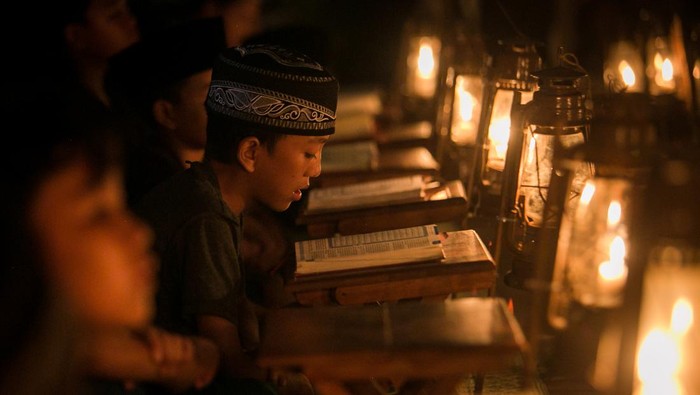 Membaca Al-Quran menyambut Lailatul Qadar Seorang pembimbing mengajarkan seorang anak mengaji dengan penerangan lampu lilin saat pengajian Tadarus Al Quran di kampung Prajurit Wirotamtomo, Baluwarti, Solo, Jawa Tengah, Rabu (3/4/2024). Pengajian dalam rangka menyambut malam Lailatul Qadar tersebut untuk mendekatkan anak-anak dengan alam serta mendidik untuk rajin membaca Al Quran terutama pada bulan Ramadhan. ANTARA FOTO/Mohammad Ayudha/Spt.