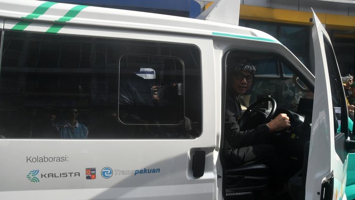 Anggota Polresta Bogor Kota mengamati angkot listrik saat uji coba di Halte Cidangiang, Kota Bogor, Jawa Barat, Kamis (4/4/2024). Pemerintah Kota Bogor melakukan uji coba lima unit angkot listrik Bogor (Alibo) dengan 30 titik pemberhentian yang menggunakan sistem pembayaran nontunai dengan tarif Rp5 ribu untuk sekali perjalanan. ANTARA FOTO/Arif Firmansyah/nym.