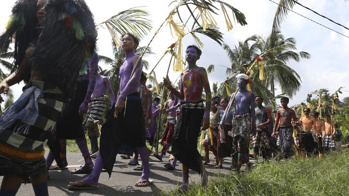 Body-painted men parade as they participate in the Hindu ritual of Ngerebeg at Tegallalang village in Bali, Indonesia on Wednesday, April 3, 2024. In this ritual, participants paint their bodies with colorful paint and parade around their village to ward off evil spirits and bring happiness to the village. (AP Photo/Firdia Lisnawati)