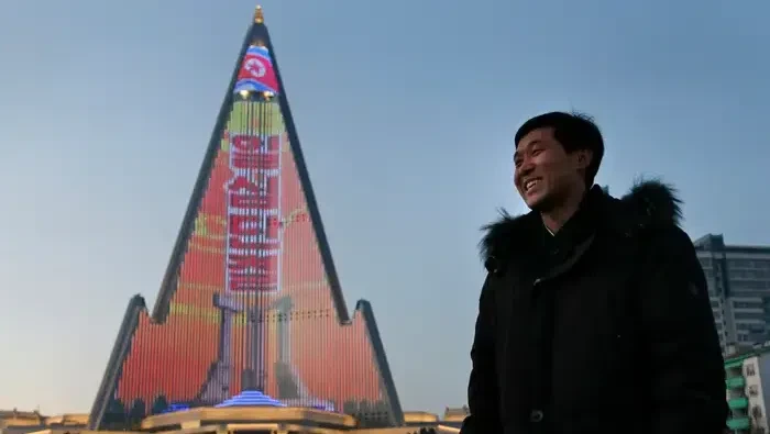Desainer Kim Yong Il berdiri di samping pertunjukan cahayanya di fasad Hotel Ryugyong