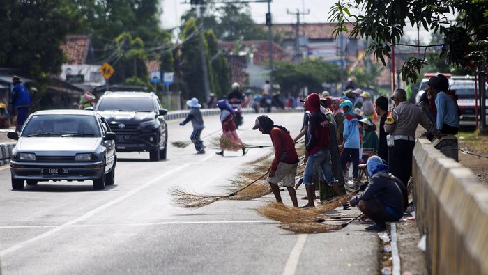 Sejumlah warga menunggu pengendara memberi sedekah dengan melempar uang di Jembatan Sewo, Jalur Pantura Sukra Indramayu, Jawa Barat, Jumat (5/4/2024). Aksi mengambil uang sedekah menggunakan sapu tersebut dapat membahayakan keselamatan pengguna jalan terutama saat arus mudik. ANTARA FOTO/Dedhez Anggara/foc.