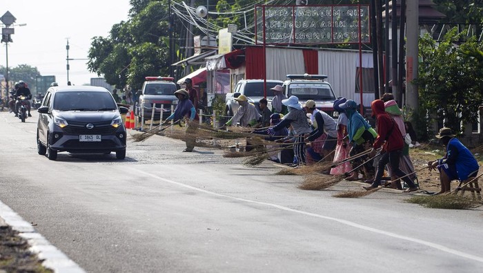 Sejumlah warga menunggu pengendara memberi sedekah dengan melempar uang di Jembatan Sewo, Jalur Pantura Sukra Indramayu, Jawa Barat, Jumat (5/4/2024). Aksi mengambil uang sedekah menggunakan sapu tersebut dapat membahayakan keselamatan pengguna jalan terutama saat arus mudik. ANTARA FOTO/Dedhez Anggara/foc.