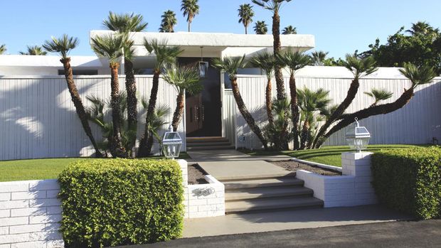Palm Springs, California, USA - March 17,2013: Exterior front view of home built in the mid 20th century. Privacy walls. Artistic landscaping with Palm trees and hedges. Low Profile.