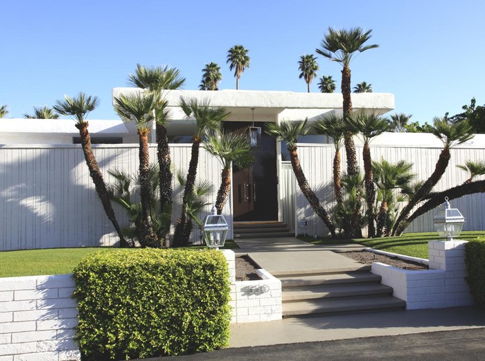 Palm Springs, California, USA - March 17,2013: Exterior front view of home built in the mid 20th century. Privacy walls. Artistic landscaping with Palm trees and hedges. Low Profile.